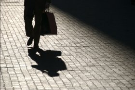 Image of a shopper in shadow carrying a shopping bag