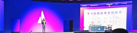 Image of Anu Bharadwaj on stage with a presentation on a large screen