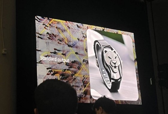 A presentation slide depicting a wristband with the stylized face of a panther in place of a watch face, captioned with the words 'Standard output.'