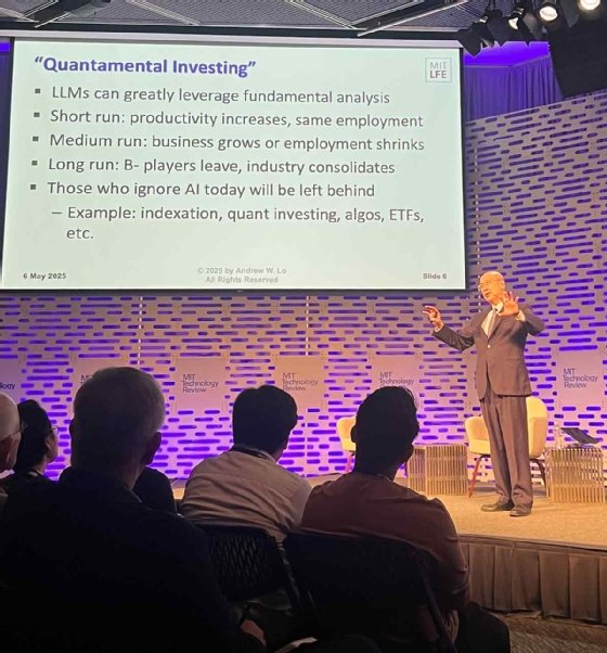 Photo of Andrew Lo standing onstage at MIT EmTech AI with a PowerPoint slide defining the three stages of generative AI ROI.