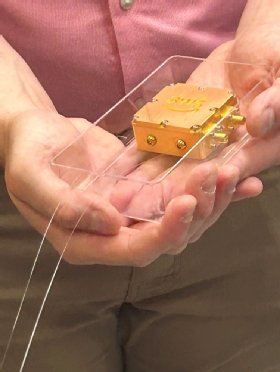 Nicholas Mondrik, quantum research scientist at AWS holds a prototype AWS quantum memory chip.