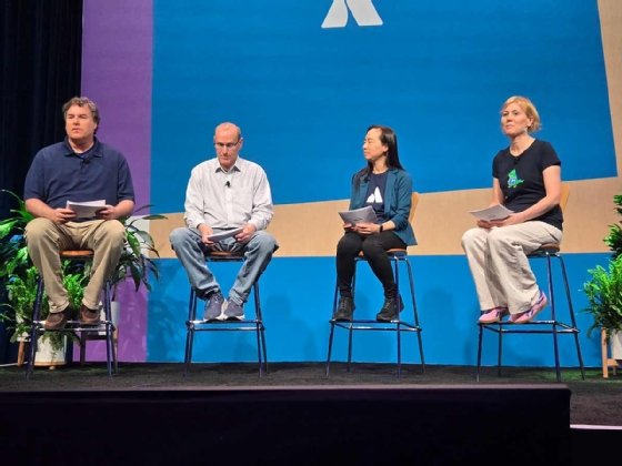 Four people seated on stage at the Atlassian Team '25 conference.