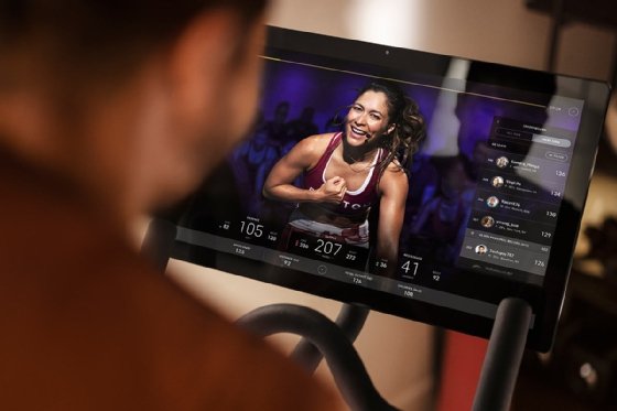 Close up of a Peloton bike screen showing a fitness instructor and user data.