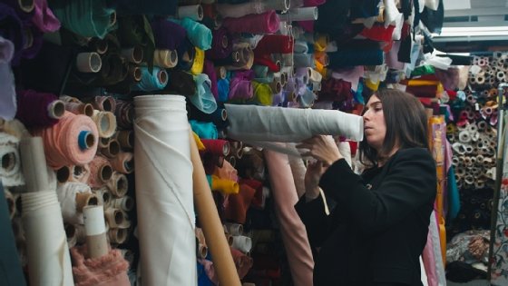 This shows Queen of Raw CEO Stephanie Benedetto inspecting rolls of textiles that usually go into landfills after going unused.