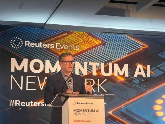 Tom Hale stands at a podium at Momentum AI New York 2025.