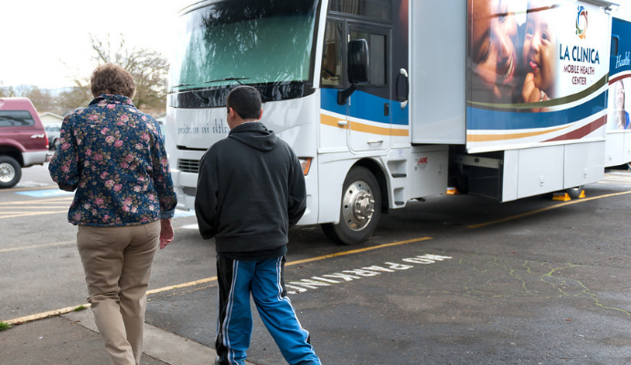 A nurse walks a student to his school\u2019s parking lot for a checkup on the La Clinica Mobile Health Center. The center makes weekly stops at a number of community sites.